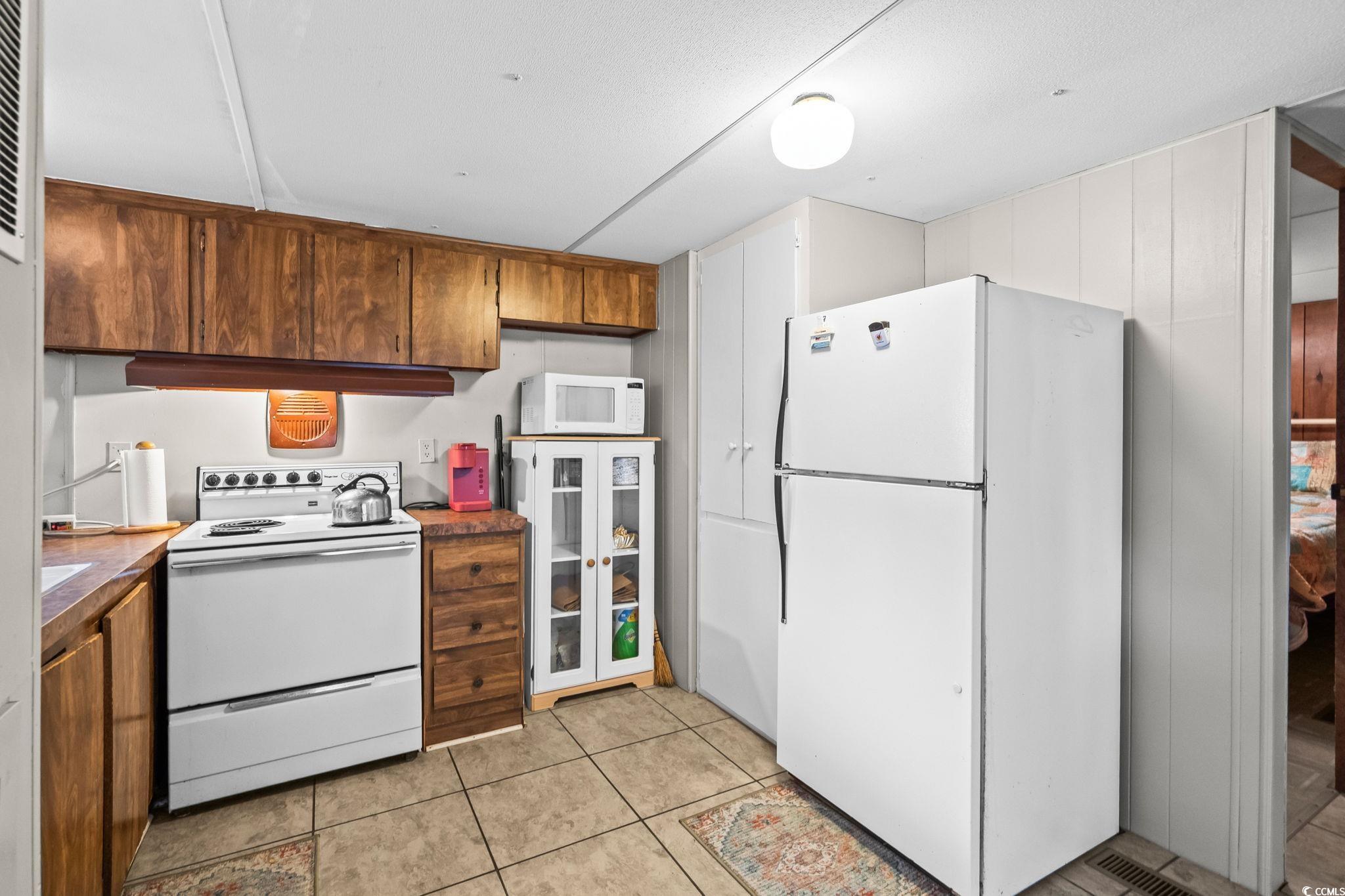 4516 Willet Street North Myrtle Beach, SC 29582 - Photo 15 of 40 Kitchen with white appliances, dark countertops, light tile patterned flooring, and a heating unit