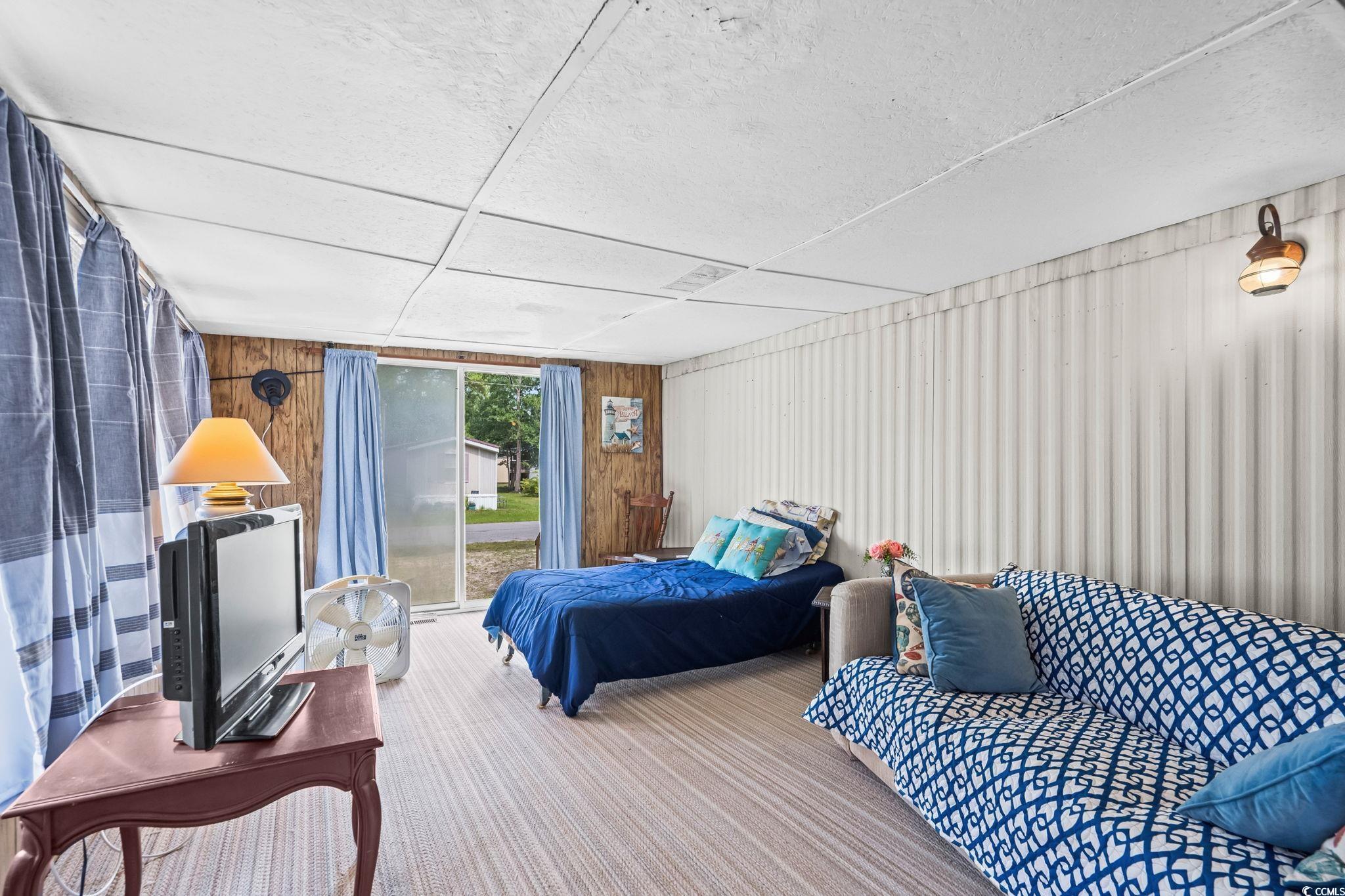4516 Willet Street North Myrtle Beach, SC 29582 - Photo 23 of 40 Bedroom featuring wooden walls, access to outside, and carpet flooring