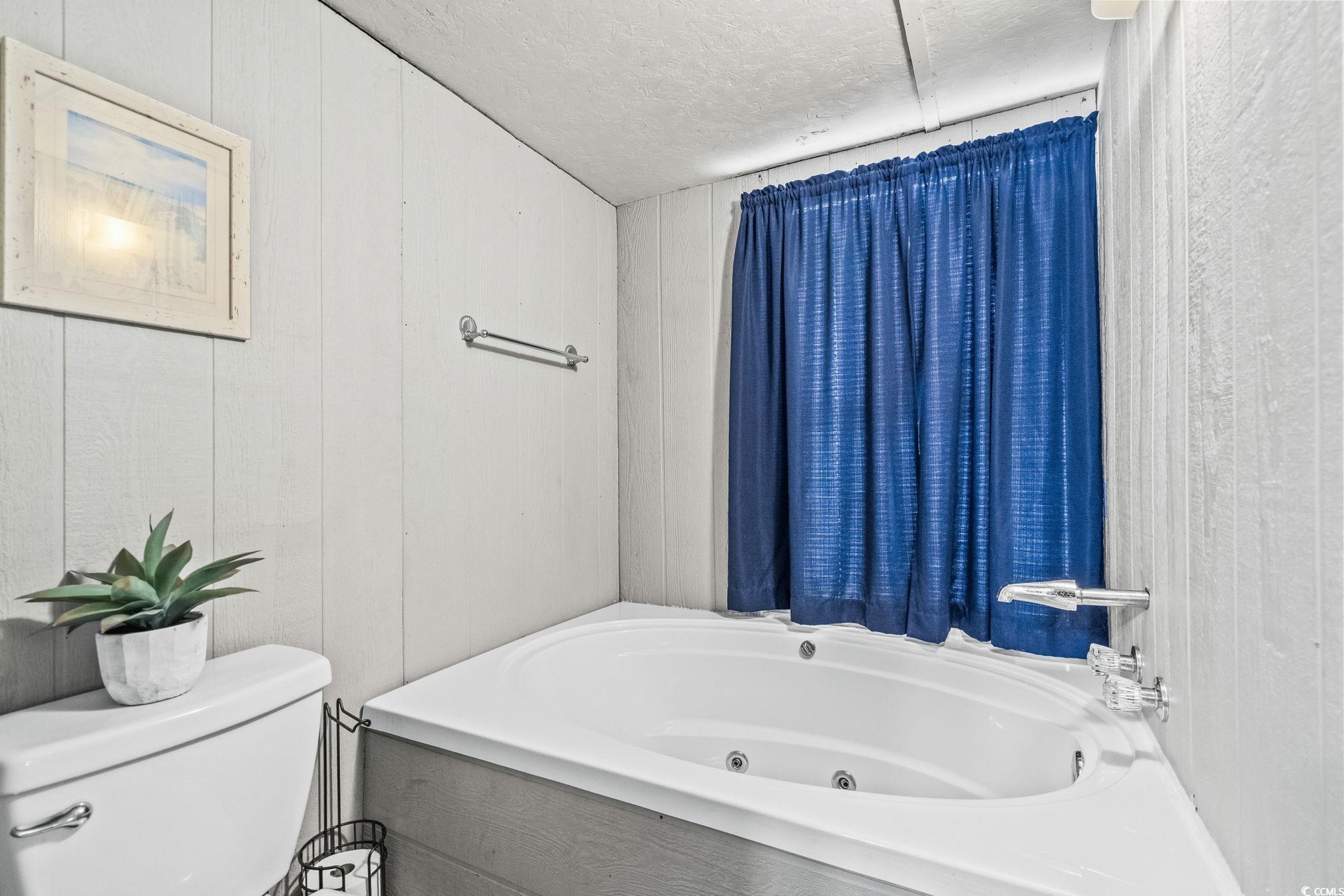 4516 Willet Street North Myrtle Beach, SC 29582 - Photo 27 of 40 Bathroom with wooden walls, a tub with jets, and a textured ceiling