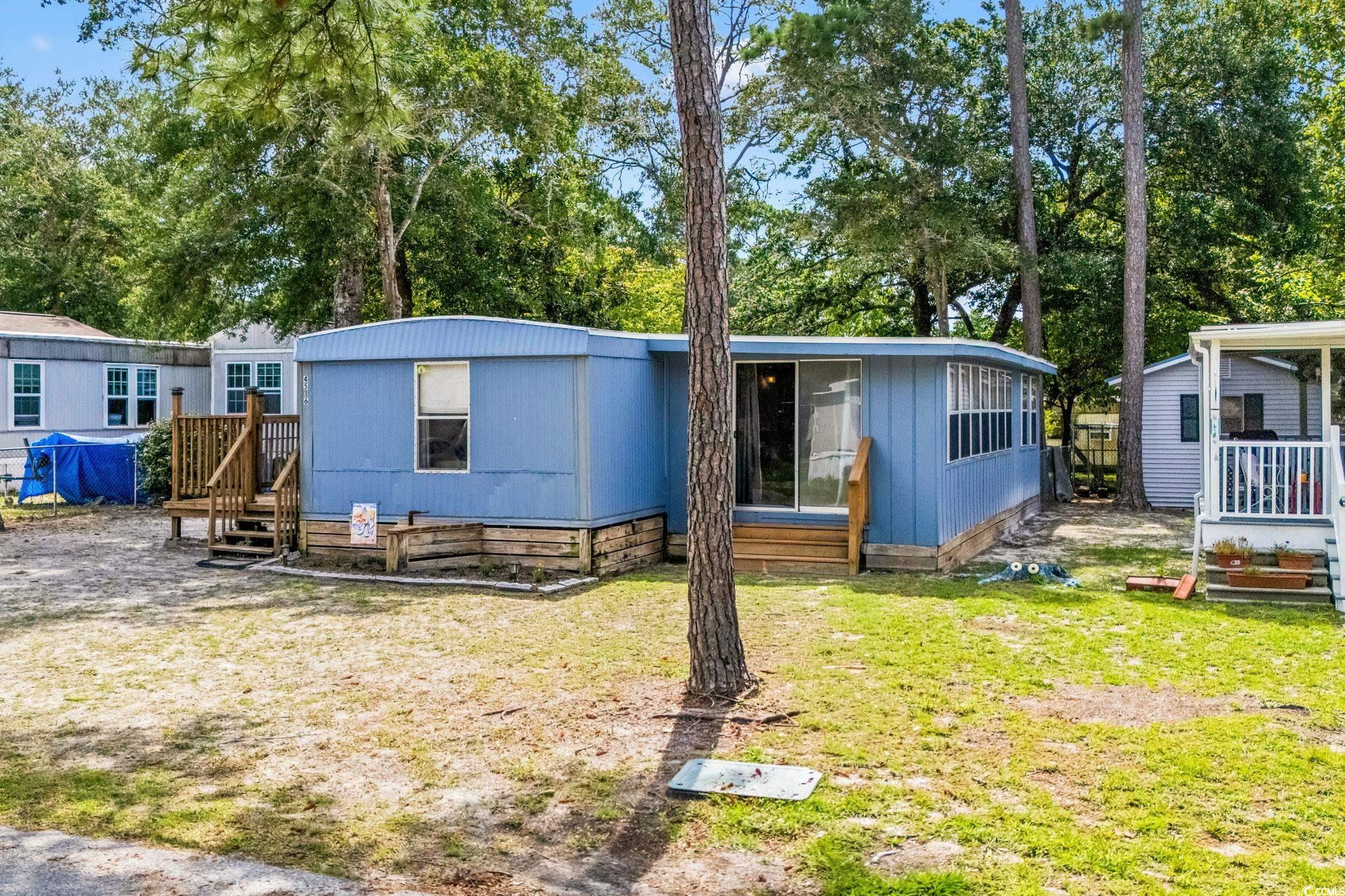 4516 Willet Street North Myrtle Beach, SC 29582 - Photo 35 of 40 Manufactured / mobile home with view of scattered trees, a wooden deck, and a front yard