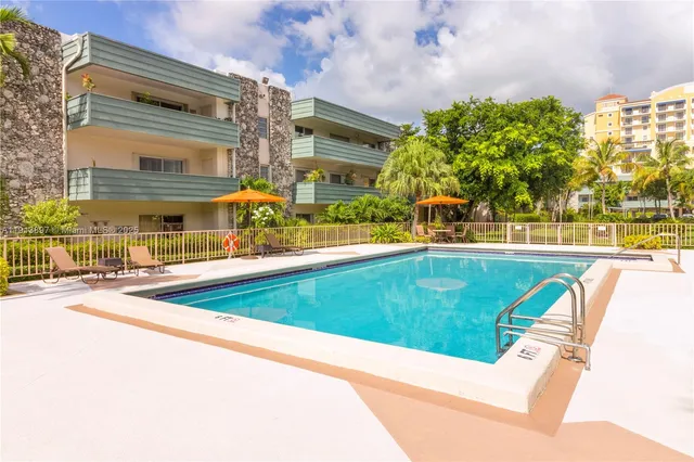 a view of a swimming pool with a lawn chairs under an umbrella