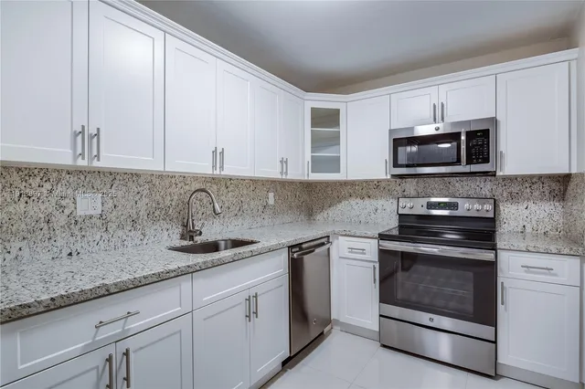 a kitchen with granite countertop white cabinets and stainless steel appliances