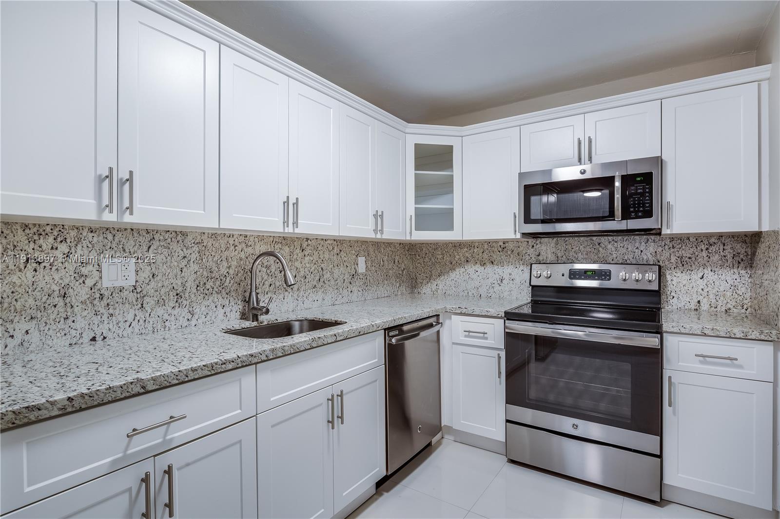8305 Southwest 72nd Avenue, Unit 105A Miami, FL 33143 - Photo 5 of 25 a kitchen with granite countertop white cabinets and stainless steel appliances