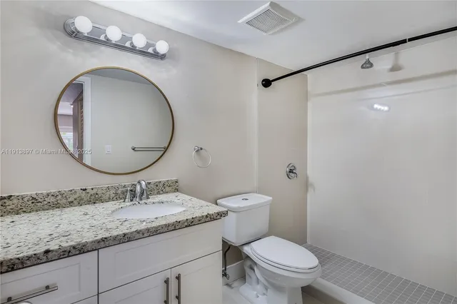 a bathroom with a granite countertop toilet sink and mirror