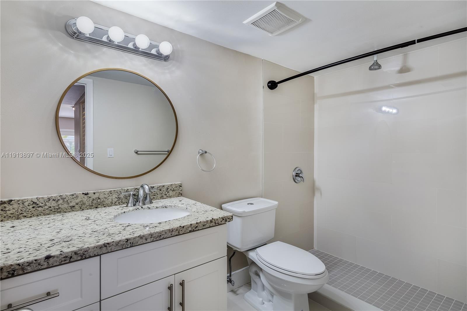 8305 Southwest 72nd Avenue, Unit 105A Miami, FL 33143 - Photo 10 of 25 a bathroom with a granite countertop toilet sink and mirror