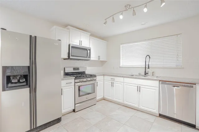 a kitchen with white cabinets sink and stainless steel appliances