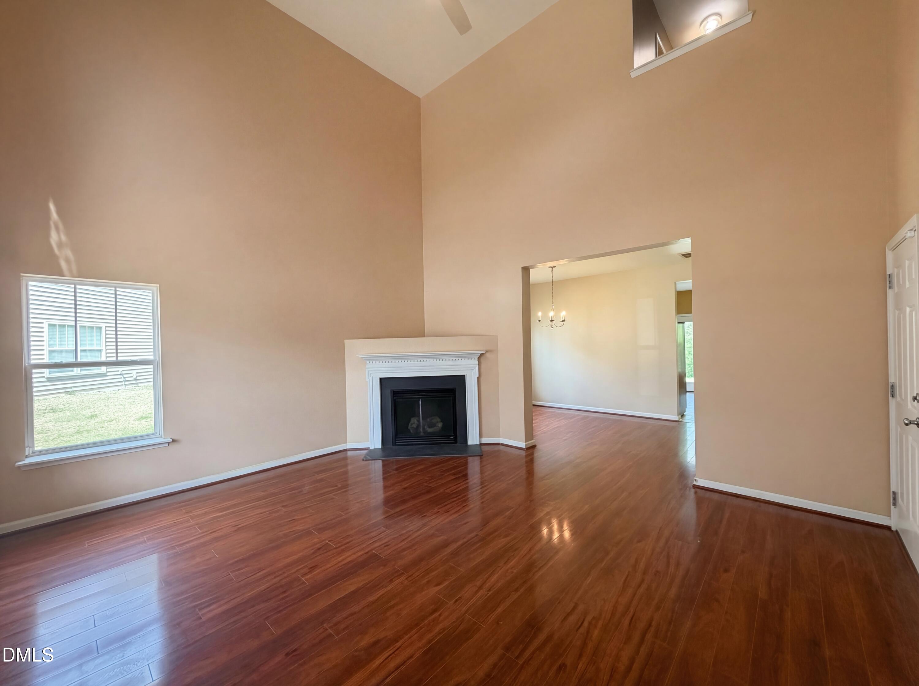 3712 Mayfair Mill Drive Raleigh, NC 27616 - Photo 3 of 16 an empty room with wooden floor fireplace and windows