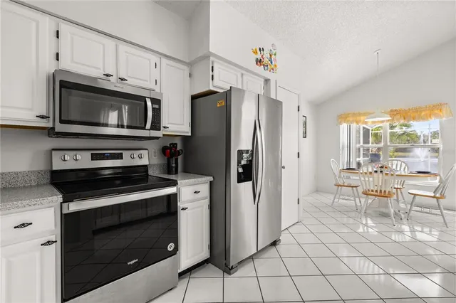 a kitchen with granite countertop a refrigerator stove and microwave