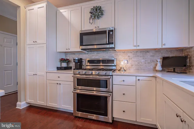 a kitchen with stainless steel appliances kitchen island granite countertop a dining table chairs and a refrigerator