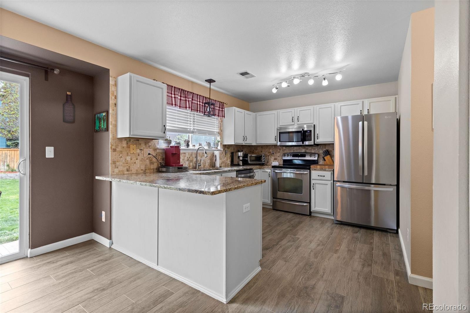 10565 Hyacinth Place Highlands Ranch, CO 80129 - Photo 11 of 33 a kitchen with granite countertop stainless steel appliances a refrigerator cabinets and wooden floor