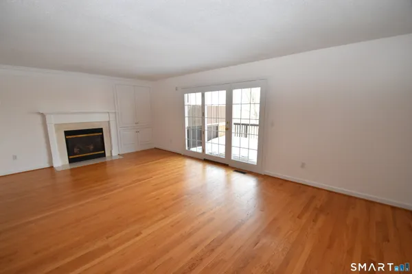 an empty room with wooden floor a fireplace and windows
