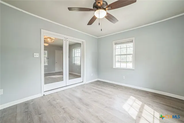 an empty room with chandelier fan and windows
