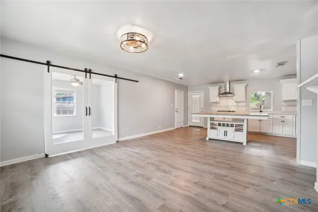 a room with stainless steel appliances kitchen island wooden floors and view living room