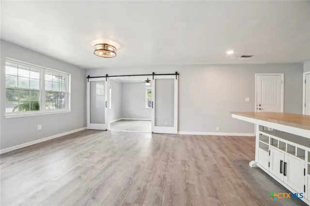 a view of an empty room with wooden floor and a window