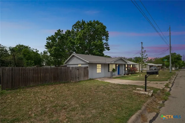 a view of a small yard in front of a house with wooden fence
