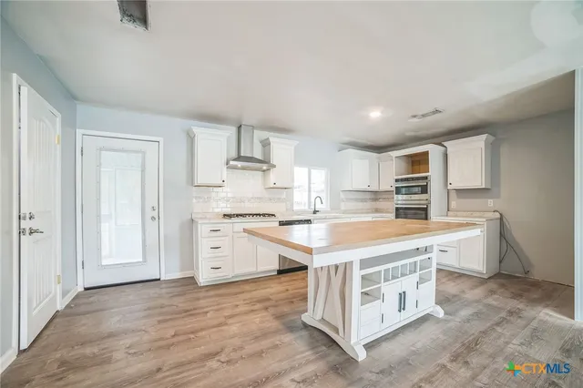 a large kitchen with kitchen island a sink a stove a refrigerator and white cabinets