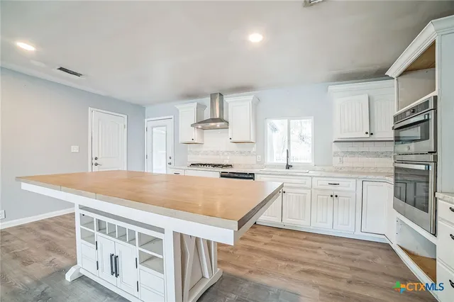 a kitchen with stainless steel appliances granite countertop a stove and white cabinets