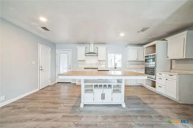 a large kitchen with kitchen island a sink stainless steel appliances and cabinets