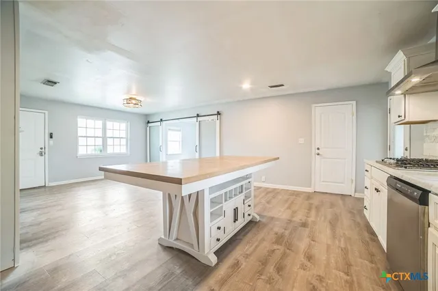 a kitchen with stainless steel appliances granite countertop a stove and a white cabinets