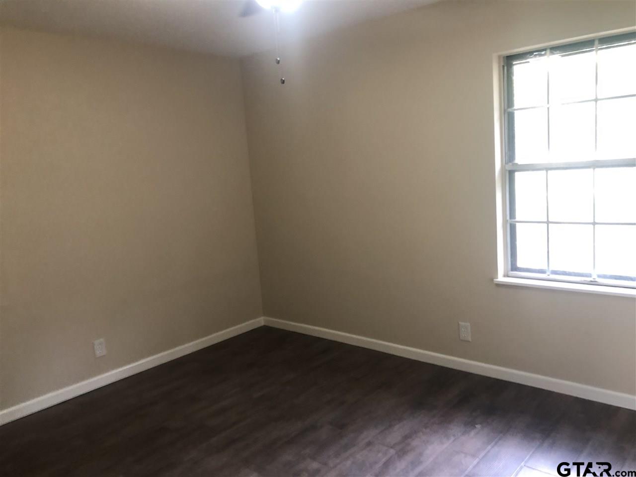 3001 South Robertson Avenue Tyler, TX 75701 - Photo 11 of 12 an empty room with wooden floor and windows
