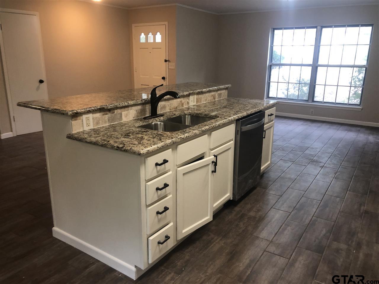 3001 South Robertson Avenue Tyler, TX 75701 - Photo 5 of 12 a kitchen with stainless steel appliances granite countertop a sink dishwasher a stove a dining table and chairs with wooden floor