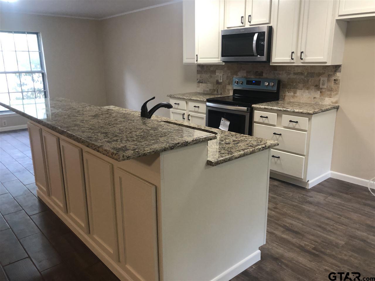3001 South Robertson Avenue Tyler, TX 75701 - Photo 6 of 12 a kitchen with stainless steel appliances granite countertop a sink stove and microwave
