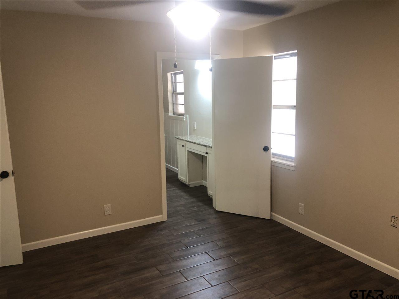 3001 South Robertson Avenue Tyler, TX 75701 - Photo 8 of 12 an empty room with wooden floor and windows