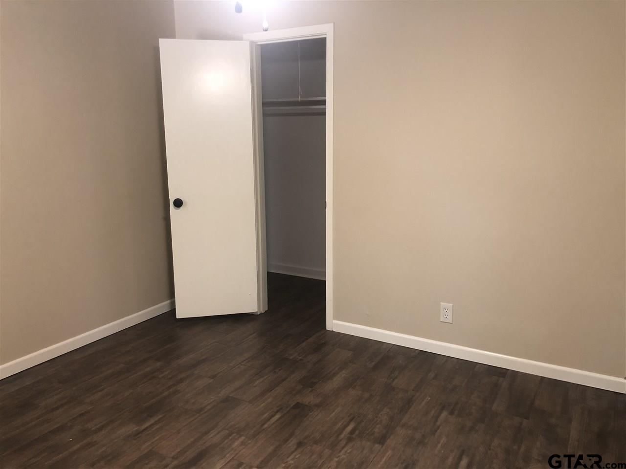 3001 South Robertson Avenue Tyler, TX 75701 - Photo 10 of 12 a view of an empty room with wooden floor and closet