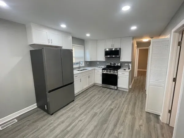 a kitchen with stainless steel appliances granite countertop a refrigerator and a stove top oven