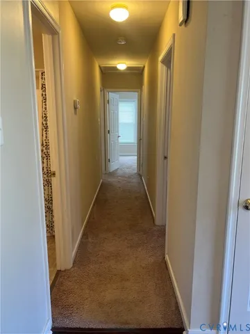 a view of a hallway with wooden floor and a bathroom