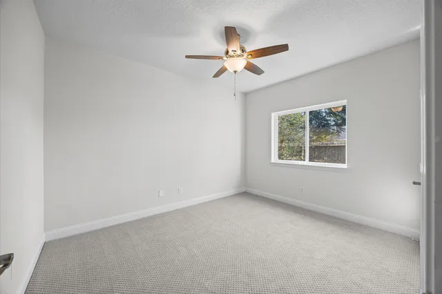 an empty room with a window and a fan