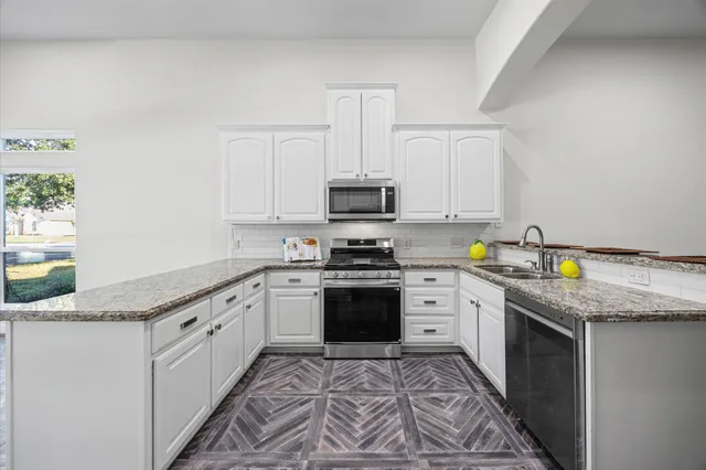 a kitchen with granite countertop a sink stove and cabinets