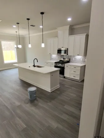 a kitchen with kitchen island a sink stainless steel appliances and wooden floor