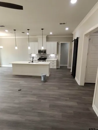 a large white kitchen with a sink a refrigerator and wooden floor