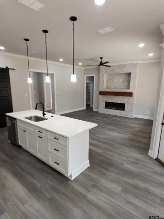 a large white kitchen with a sink a fireplace and wooden floor