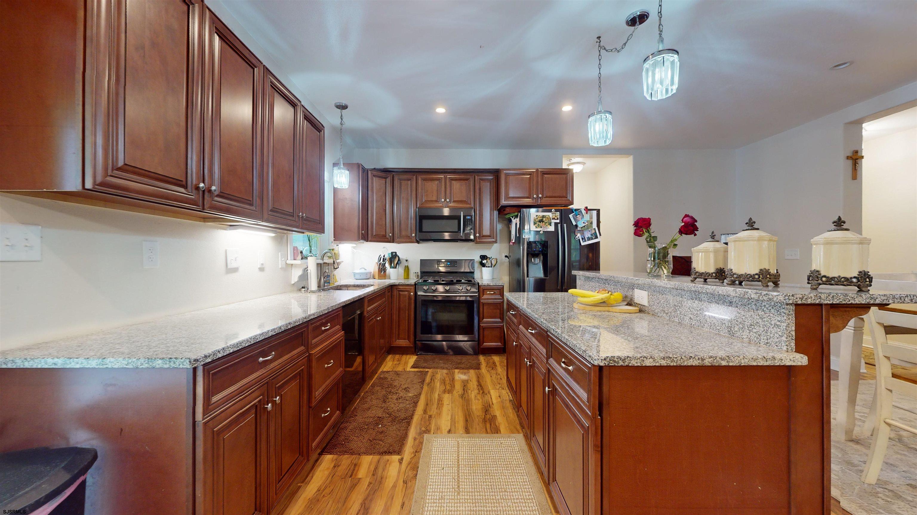 181 3rd Estell Manor, NJ 08319 - Photo 6 of 34 a kitchen with kitchen island granite countertop wooden floors wooden cabinets a center island and stainless steel appliances