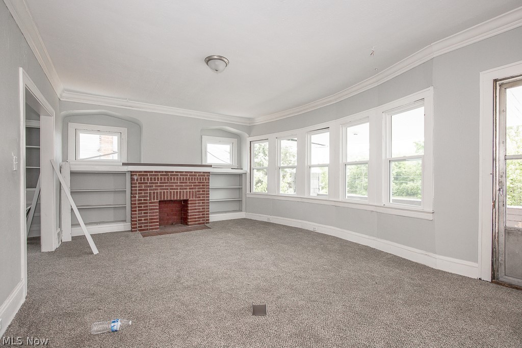 1000 Eddy Road Cleveland, OH 44108 - Photo 21 of 38 Unfurnished living room featuring carpet flooring, ornamental molding, and a fireplace