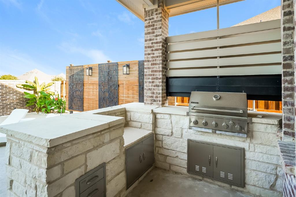 2000 Johnson Road Mansfield, TX 76063 - Photo 11 of 27 Outdoor kitchen featuring a built-in stainless steel grill, stone veneer base, and integrated storage