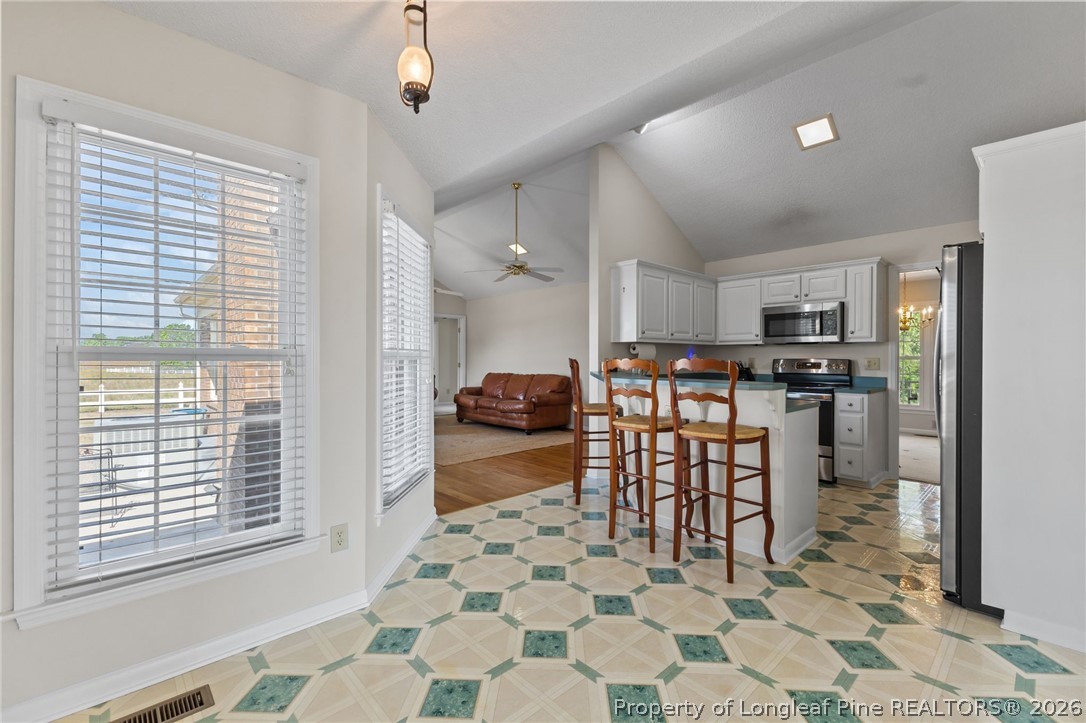 203 White Oak Church Road Clinton, NC 28328 - Photo 21 of 49 a kitchen with stainless steel appliances kitchen island granite countertop a refrigerator a sink a stove a dining table and chairs with wooden floor