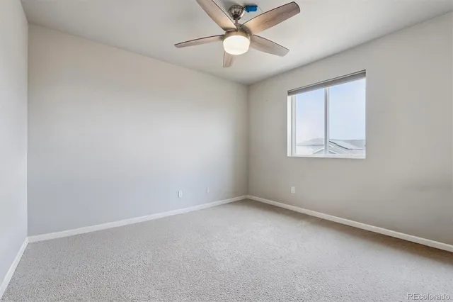 an empty room with a window and ceiling fan