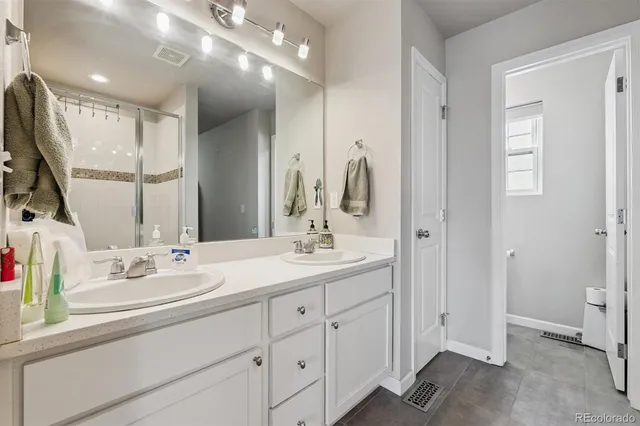 a bathroom with a double vanity sink a mirror and a shower