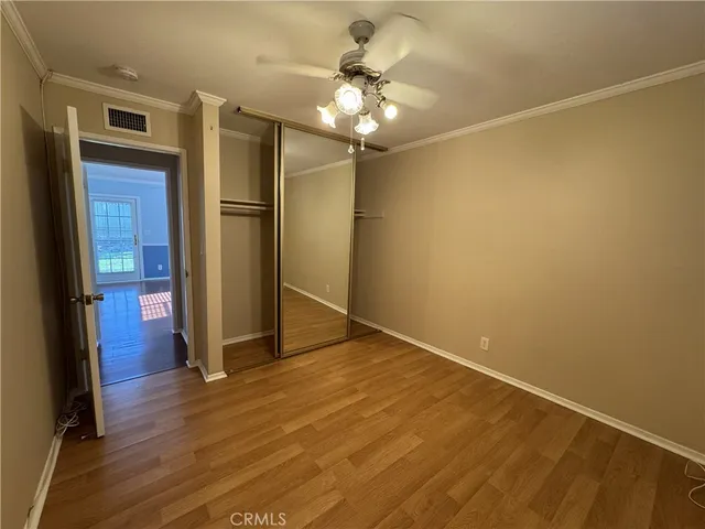 an empty room with wooden floor and a ceiling fan