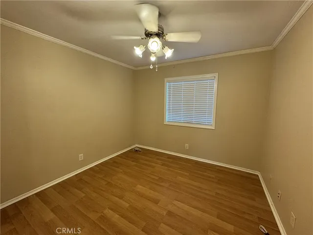 a view of an empty room with wooden floor and a chandelier fan