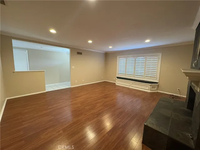a view of an empty room with wooden floor and a fireplace