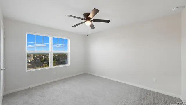 an empty room with a window and a fan