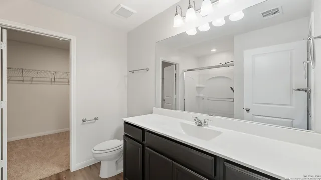 a bathroom with a sink a toilet a large mirror and shower