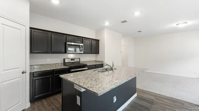 a kitchen with stainless steel appliances granite countertop a sink stove and microwave