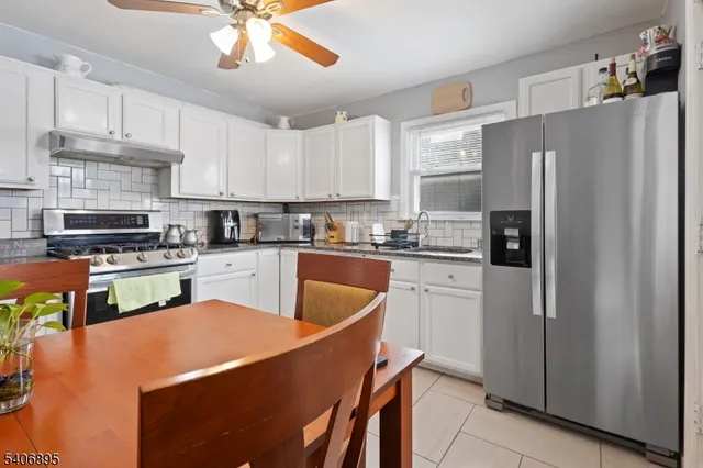 a kitchen with stainless steel appliances granite countertop a refrigerator a sink dishwasher a stove and white cabinets with wooden floor