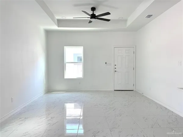 an empty room with windows and fan