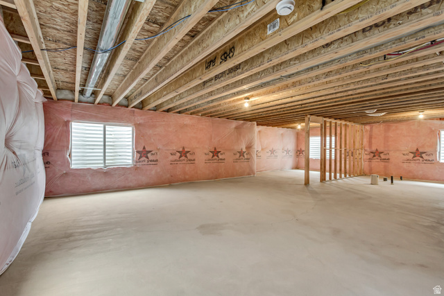 1389 1440 East, Unit 1 Payson, UT 84651 - Photo 16 of 17 Unfinished basement featuring exposed wood joists, concrete flooring, pink insulation, multiple windows, and partial wood framing